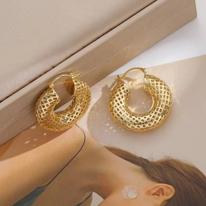 Minimalist gold hollow metal hoop earrings for women presented on a beige stand