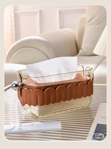 Close-up of transparent tissue box with brown wave trim and gold ball handle
