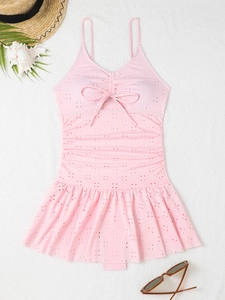 Detail of pink one-piece swim dress featuring hollow embroidery and scalloped hemline