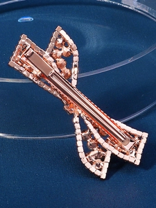 Close-up of sparkling rose gold rhinestone bow hair clip with polished metal finish