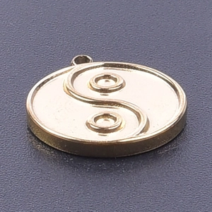 Macro detail of 18k gold plated Tai Chi pendant with Yin Yang engraving on textured grey