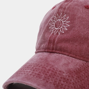 Détail d'une casquette en coton délavé avec broderie blanche et texture de couture