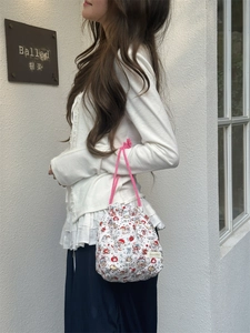 Detailed view of quilted drawstring storage bag with cartoon print and pink woven handles