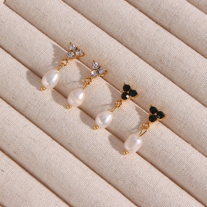 Detailed macro view of 18K gold plated pearl earrings with green and clear gemstones