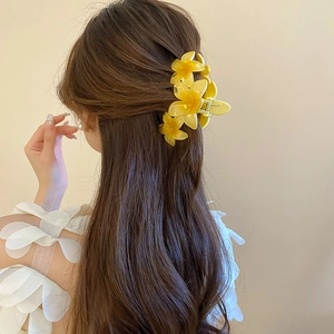 Detail of yellow acrylic plumeria flower hair claw clip on female model back head