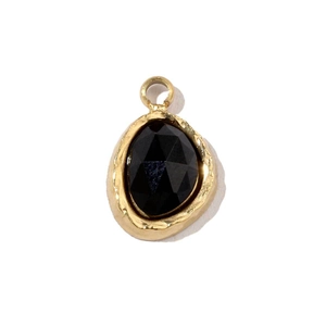 Détail d'un pendentif trèfle doré avec pierre naturelle noire et texture martelée