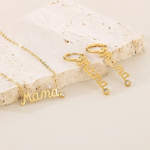 Detail of gold Mama necklace and earring set with crystals on a textured stone base