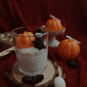 Close-up of Halloween scented candle with orange pumpkin and black bat wax decorations
