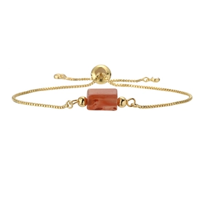 Detail of adjustable gold bracelet featuring an orange-red rectangular gemstone stone