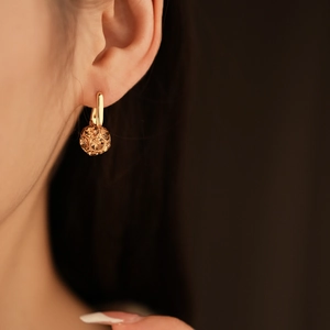 Detailed side view of a gold-plated earring featuring a champagne crystal pavé ball charm