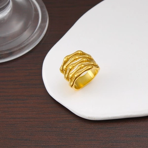 Detail shot of golden geometric bone-shaped wide ring on a white display cushion