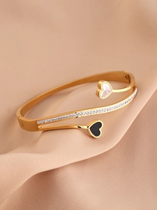 Detailed shot of gold heart bracelet featuring white shell, black inlay and crystals