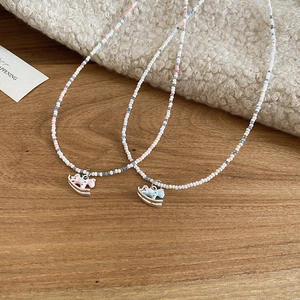 Détail de colliers de perles colorées avec pendentifs poneys en émail bleu et rose