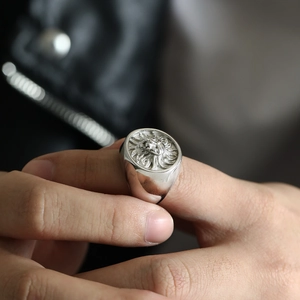 Close-up of vintage lion head seal ring on finger with detailed metallic relief
