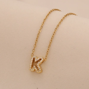 Detailed view of a gold letter K pendant necklace with sparkling crystal inlay