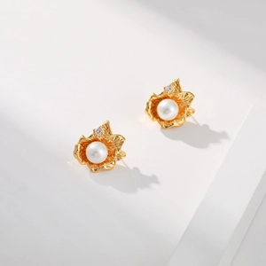 Detailed view of gold petal earrings with white pearls and small zircon on white steps