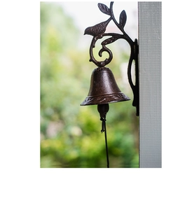 Detailed view of vintage cast iron doorbell with bird and leaf motif on white frame