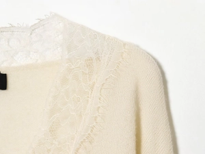 Close-up of wool blend knit sweater featuring delicate floral lace trim and soft texture