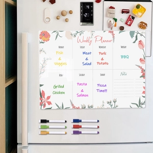 Close-up of magnetic acrylic weekly planner on fridge with floral design and colorful markers