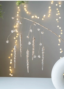 Macro shot of clear acrylic icicles and crystal drops on golden branch for Christmas decor
