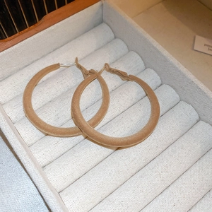 Detail of light beige flocked velvet texture on round geometric hoop earrings for women