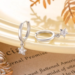 Élégantes boucles d'oreilles en argent et zircon sur plateau avec pages de livre vintage