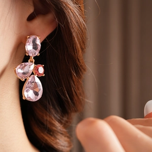 Detail shot of vintage style gold drop earrings with large pink and red gemstones