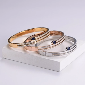 Three sleek snake-shaped metal bangles in gold and silver with blue stones and crystals