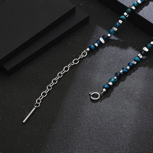 Détail des perles en pierre œil de chat bleu et des entretoises en acier sur la chaîne