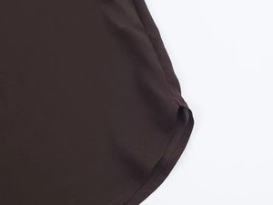 Dettaglio dell'orlo curvo di una camicia a maniche lunghe marrone scuro in tessuto liscio