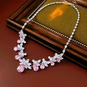 Détail du collier de zircons roses taille poire sur un fond en cuir vintage rouge foncé