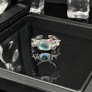 Macro view of moonstone ring with pink and white gemstones on a reflective surface