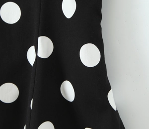 Vue détaillée du tissu tissé à pois noirs et blancs montrant la texture et le drapé