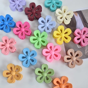 Flat lay of large flower hair claws in assorted matte candy colors on white background