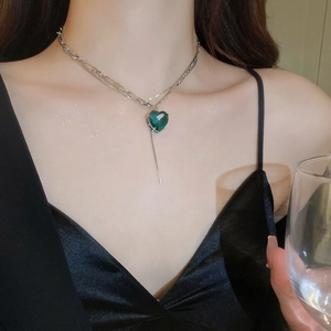 Detail of elegant double-layered silver necklace with green heart-shaped crystal pendant