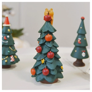 Detail of green resin Christmas tree figurine with yellow bear topper and red apple decor