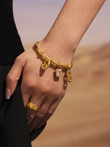 Detail showing 18k gold plated bangle with zircon figure 8 charm and textured wide ring