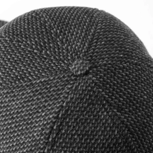 Macro shot of dark grey knit baseball cap top button and detailed weaving texture
