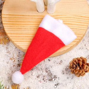 Mini red and white Christmas hat cutlery holder on wooden tray with pine cones and snow