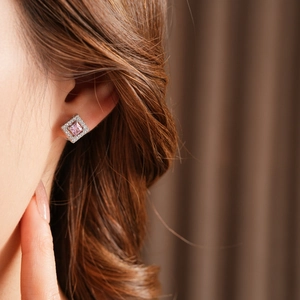 Detailed close-up of a square silver earring with a pink gemstone and small zircons