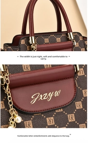 Detail of premium brown tote bag featuring dark red leather handles and elegant pearl pendant