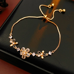 Détail du bracelet fleur dorée avec zircons posé sur un écrin en cuir noir de luxe