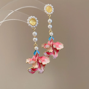Detail view of floral drop earrings with yellow sun flower and pink enamel lily charms