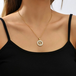 Close-up of a gold circle cross necklace with white zircons on a female model