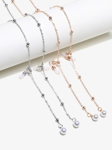 Detail of gold and silver eyeglass chains with pearls and silicone loops on white props