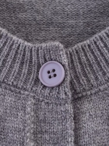 Close-up of grey knit cardigan neckline with ribbed trim and purple button detail