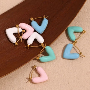 Detail view of heart-shaped 18K gold-plated enamel earrings in pastel colors on wood