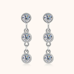 Detail of silver drop earrings featuring a vertical triple round moissanite stone design