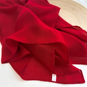 Detail of red cotton-linen scarf with fabric composition label showing 100% cotton-linen feel