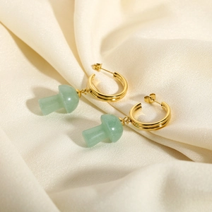 Detail of 18K gold C-shaped hoop earrings with green stone mushroom charms on silk